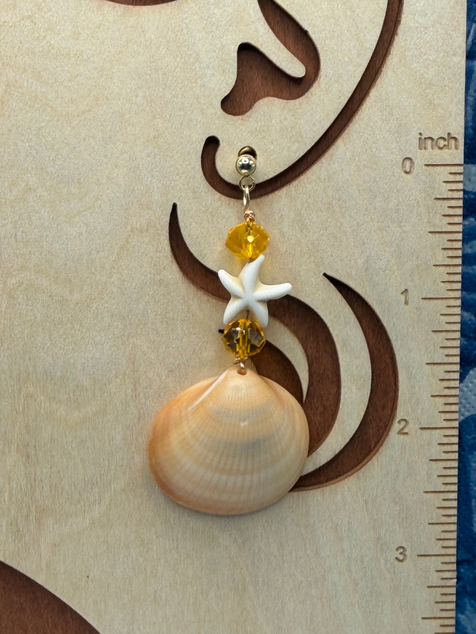 Single golden cockle shell earring on mermaid wood display with ruler showing 3 inch drop