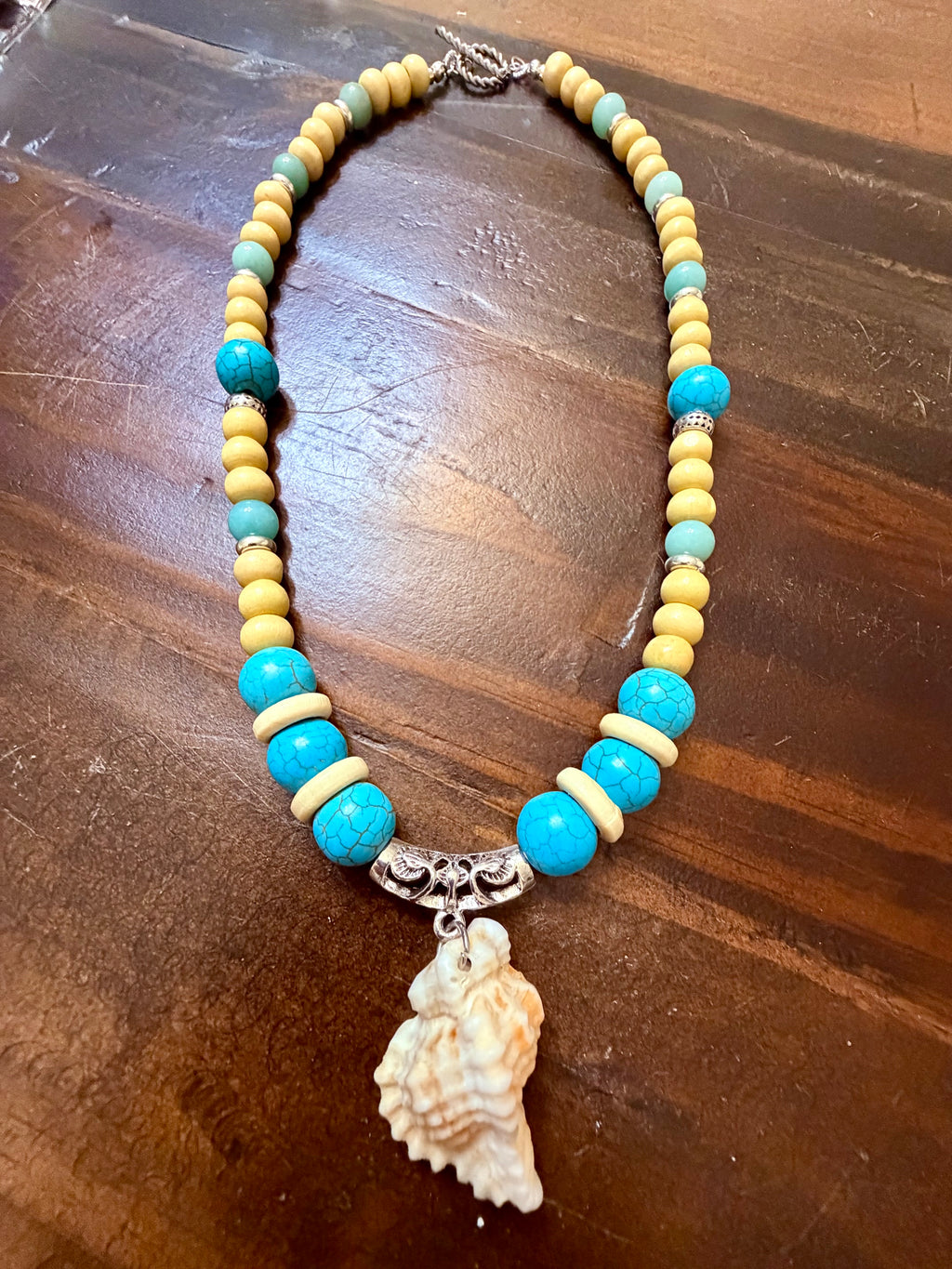 Woman wearing turquoise beaded conch shell necklace at the beach