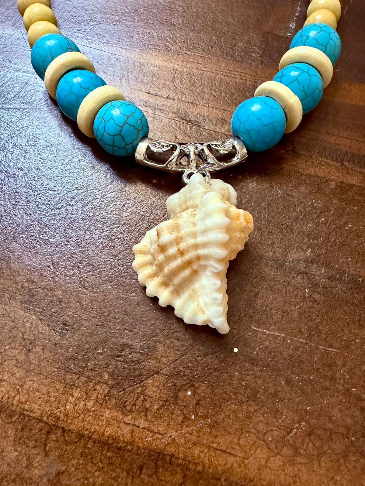 Conch shell necklace displayed on a jewelry bust