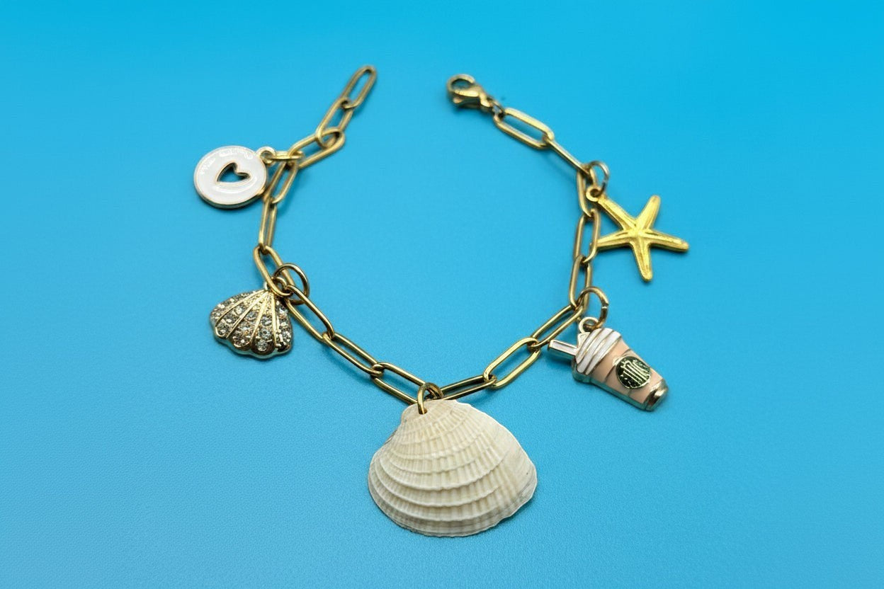 Shoreline Keepsakes gold paperclip chain bracelet featuring a real ribbed venus clam shell and assorted beach charms.